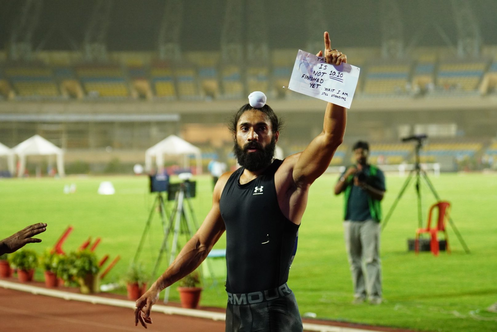 Gurindervir Singh holding a sign at an athletics track